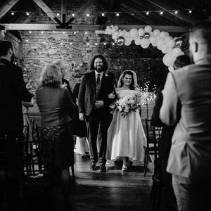 Bride and Groom walk doen the isle at Hughes craft Distillery